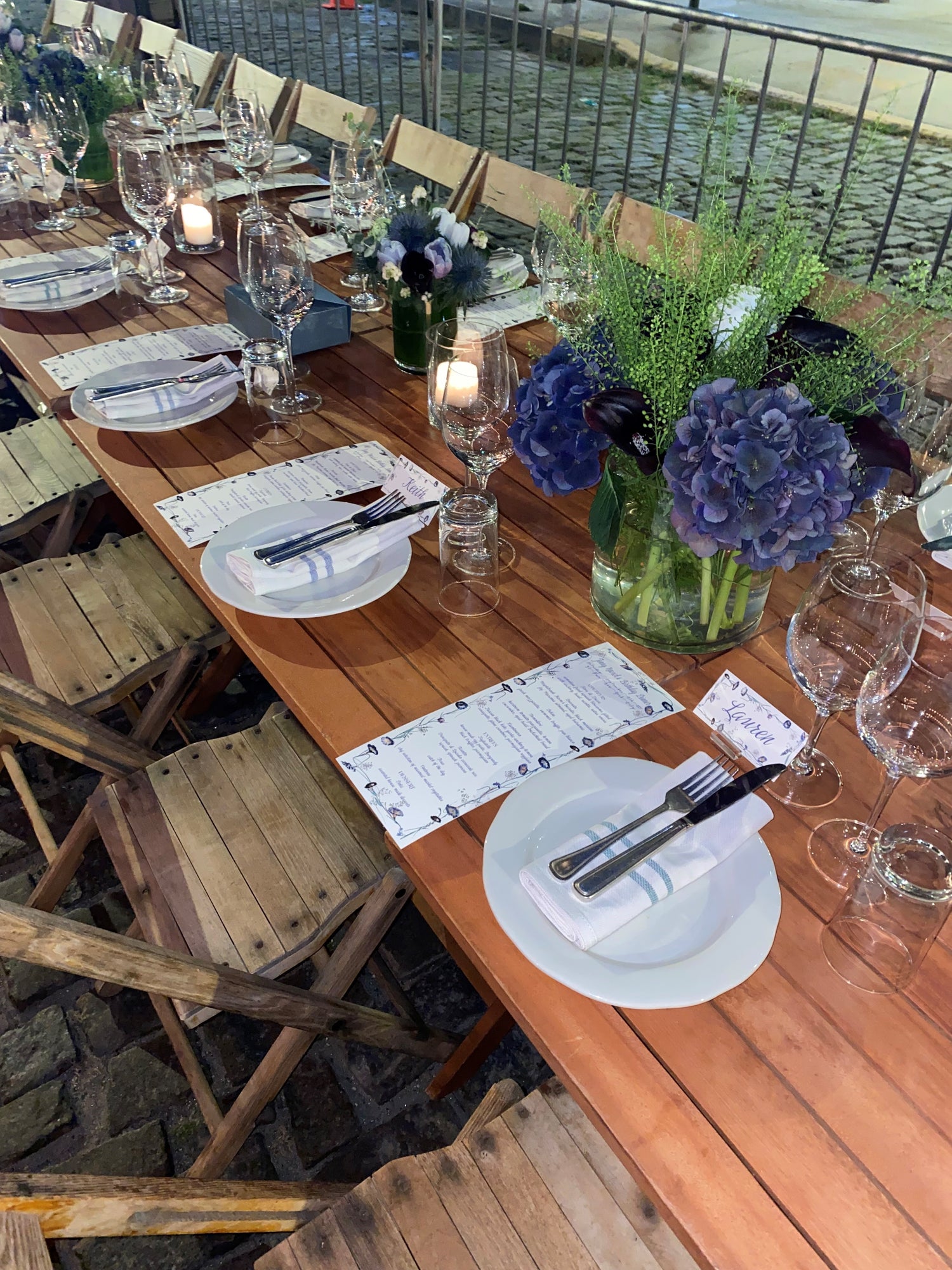 Dinner party with a beautiful tablescape. Greenery & flowers line the table with the handwritten calligraphy on the place cards & the evening's menu matcheing the florals. The table setting is elevated by the arrangements matching the event stationery. 