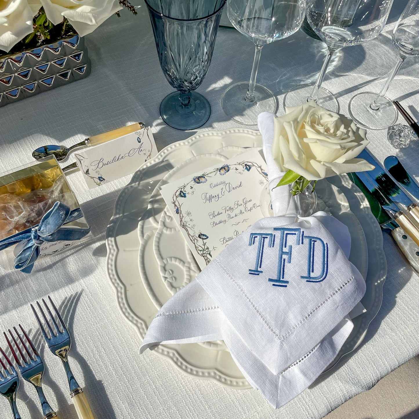 Wedding place card with elegant blue floral and butterfly border, featuring modern calligraphy name "Anna" — perfect for refined wedding tablescapes, garden receptions, and luxury bridal decor by Written Ceremony.